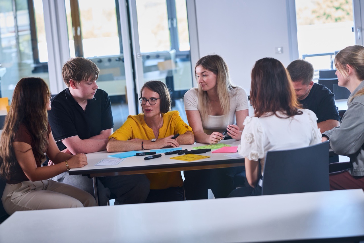 Gruppe von jungen Mitarbeitenden löst eine Gruppenaufgabe